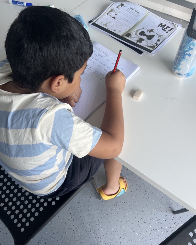 A primary student writing in his exercise book